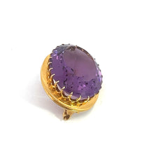 Load image into Gallery viewer, A close-up image of the Victorian 14kt Yellow Gold 24ct Oval Amethyst Brooch, featuring a large, oval-shaped purple gemstone. The brooch is held in place by intricate prongs and is set against a clean white background, exuding Victorian elegance.