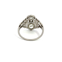 Load image into Gallery viewer, The Art Deco Platinum 1.20cttw Old Mine Cut + 1.04cttw Diamond Ring, featuring an intricate band design with geometric patterns and a central hexagonal setting holding an Old Mine cut diamond, is positioned upright against a white background, showcasing its detailed craftsmanship and elegant design.