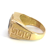 Load image into Gallery viewer, The Late Century 14kt yellow gold ring features an engraved geometric pattern on the outer band and a dark garnet gemstone surrounded by diamonds on the top. The inside of the band boasts a textured design. Positioned on its side, the ring showcases both its intricate outer and inner details.