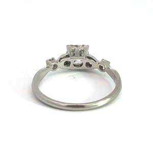 This exquisite Art Deco jewelry piece, the Platinum .50ct Old European Cut and .28cttw Old Mine Cut Diamond Ring, boasts an ornate setting with a raised design on the top. The polished platinum band curves into the detailed upper part, featuring intricate cutout patterns and small raised sections. Set against a plain white background, its elegance speaks volumes.