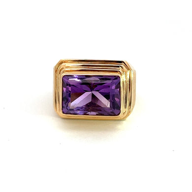 The Late Century 14kt Yellow Gold 7.5ct Amethyst Pyramid Style Ring features a captivating amethyst centerpiece with a large, rectangular purple gemstone cut with multiple facets to enhance its brilliance. The ring's 14kt yellow gold setting has intricate ridges, creating a textured and layered appearance reminiscent of a pyramid style against a plain white background.