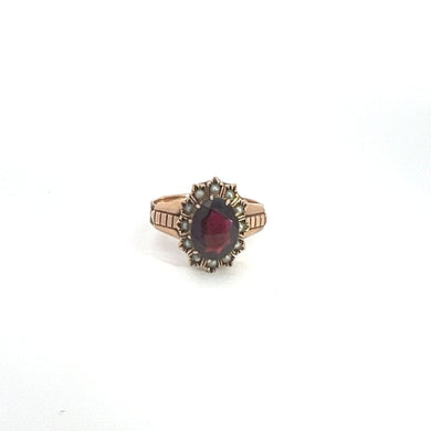 Introducing the Victorian 9KT Yellow Gold 2.75ct Garnet & Seed Pearl Ring, this gold ring boasts a large, oval-shaped red garnet set at its center. The gemstone is encircled by a decorative border that imparts an ornate, vintage appearance. Crafted from 9kt yellow gold, the band features intricate engraved details and adorned with seed pearls, enhancing its exquisite design.