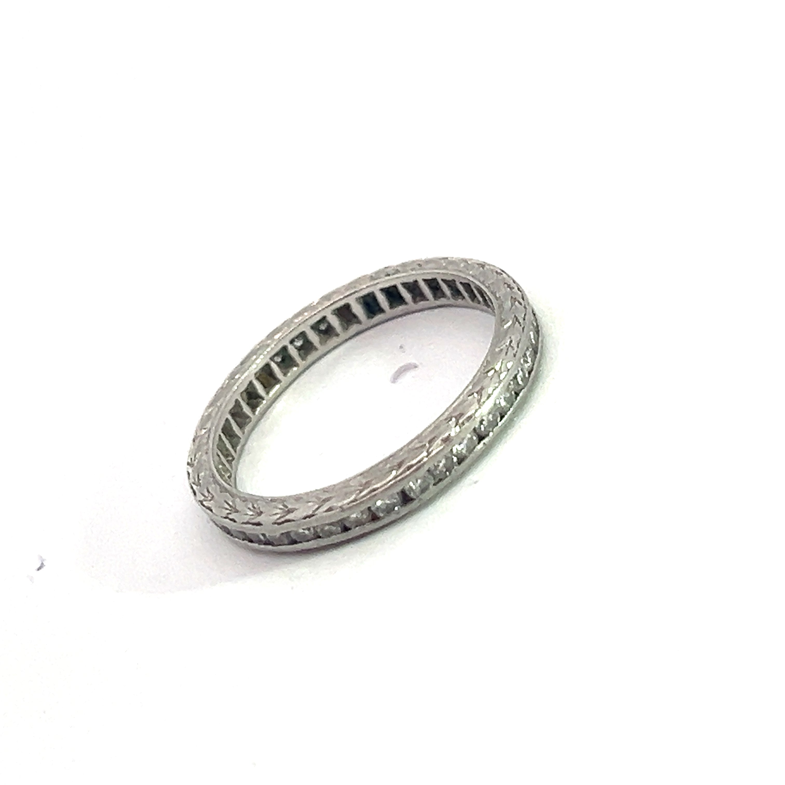 Introducing the Art Deco Platinum 1cttw Round Brilliant Cut Diamond Band, a stunning wedding ring that showcases intricate detailing and small round brilliant cut diamonds encircling its entire circumference. The ring is elegantly photographed against a plain white background.