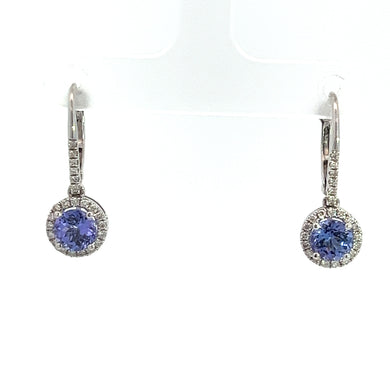 The Modern 14kt White Gold 1.83cttw Tanzanite + .35cttw Diamond Earrings feature round, blue tanzanite gemstones surrounded by a halo of small, clear diamonds. These earrings have a slender, curved design in 14kt white gold and are displayed against a white background.