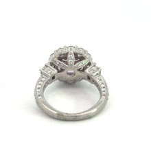 Load image into Gallery viewer, The Modern Platinum 3.30 No Heat Padparadscha Sapphire engagement ring features an ornate band and intricate setting. Its centerpiece is a rare no-heat Padparadscha sapphire, surrounded by small white stones in an elaborate floral design. The ring is photographed against a plain white background.