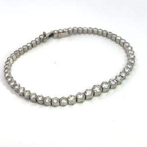 The "Art Deco Platinum 4.90cttw Diamond Bezel Set 7.25inch Bracelet" features hexagonal links, each adorned with a round, sparkling diamond in bezel settings, arranged in a seamless pattern. This exquisite Art Deco piece is displayed flat on a white surface and includes a clasp at one end.