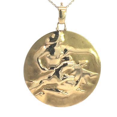 The Late Century 14kt Yellow Gold Free-form Lady With Dogs Medallion hangs from a thin gold chain, featuring a wavy, textured surface and a shiny finish that reflects light in various spots. The overall shape is slightly irregular due to its free-form design.