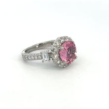 Load image into Gallery viewer, The Modern Platinum 3.30 No Heat Padparadscha Sapphire Ring features a prominent, round no-heat Padparadscha sapphire at its center, encircled by a halo of clear gemstones. The band is elegantly embellished with additional small clear gemstones and intricate designs on both sides. The ring is photographed against a plain white background.