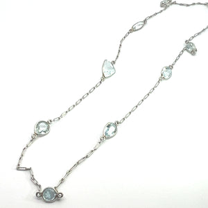 A delicate platinum necklace featuring a fine chain interspersed with approximately 5 carats of multi-shaped aquamarines, including round, oval, and teardrop. The Mid Century Platinum Approx 5ct Multi Shape Aquamarine by the Yard 20 Inch Necklace is neatly arranged on a plain white background, exuding mid-century craftsmanship.