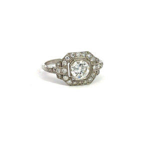 The Late Art Deco Platinum .91ct Round Brilliant Cut Diamond + 1.16cttw Diamond Ring exudes Art Deco elegance, featuring a central round brilliant cut diamond set in an ornate octagonal bezel. The ring is adorned with intricate detailing and vintage sophistication, accented by smaller surrounding diamonds on the band and bezel.