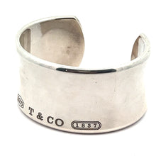 Load image into Gallery viewer, The Modern Tiffany Sterling Silver Cuff Bracelet c.2001 boasts a wide, polished design adorned with engravings of &quot;925,&quot; &quot;T &amp; CO,&quot; and the 1837 hallmark. It features a small notch opening opposite the engraved side, providing a contemporary and elegant look.