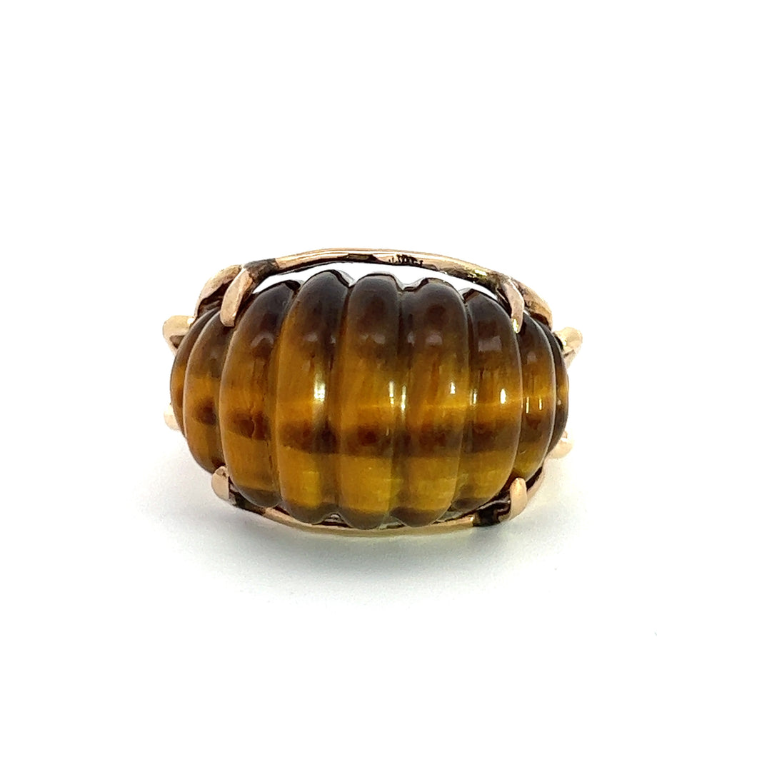 Introducing the Retro 14yg Tiger's Eye Carved Ring: a stunning piece showcasing a large cabochon-cut tiger's eye gemstone set against a ribbed design. The deep golden-brown hue of the stone, secured by delicate prongs, enhances its intricate detailing and creates an exquisite carved appearance.