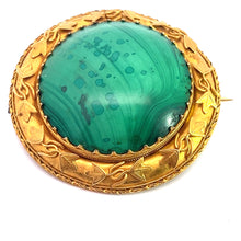 Load image into Gallery viewer, The Victorian 18ktyg Fancy Frame Malachite Brooch showcases a large, round green malachite stone with natural patterns, set in an ornate gold frame adorned with leaf motifs, exuding a vintage and elegant design.