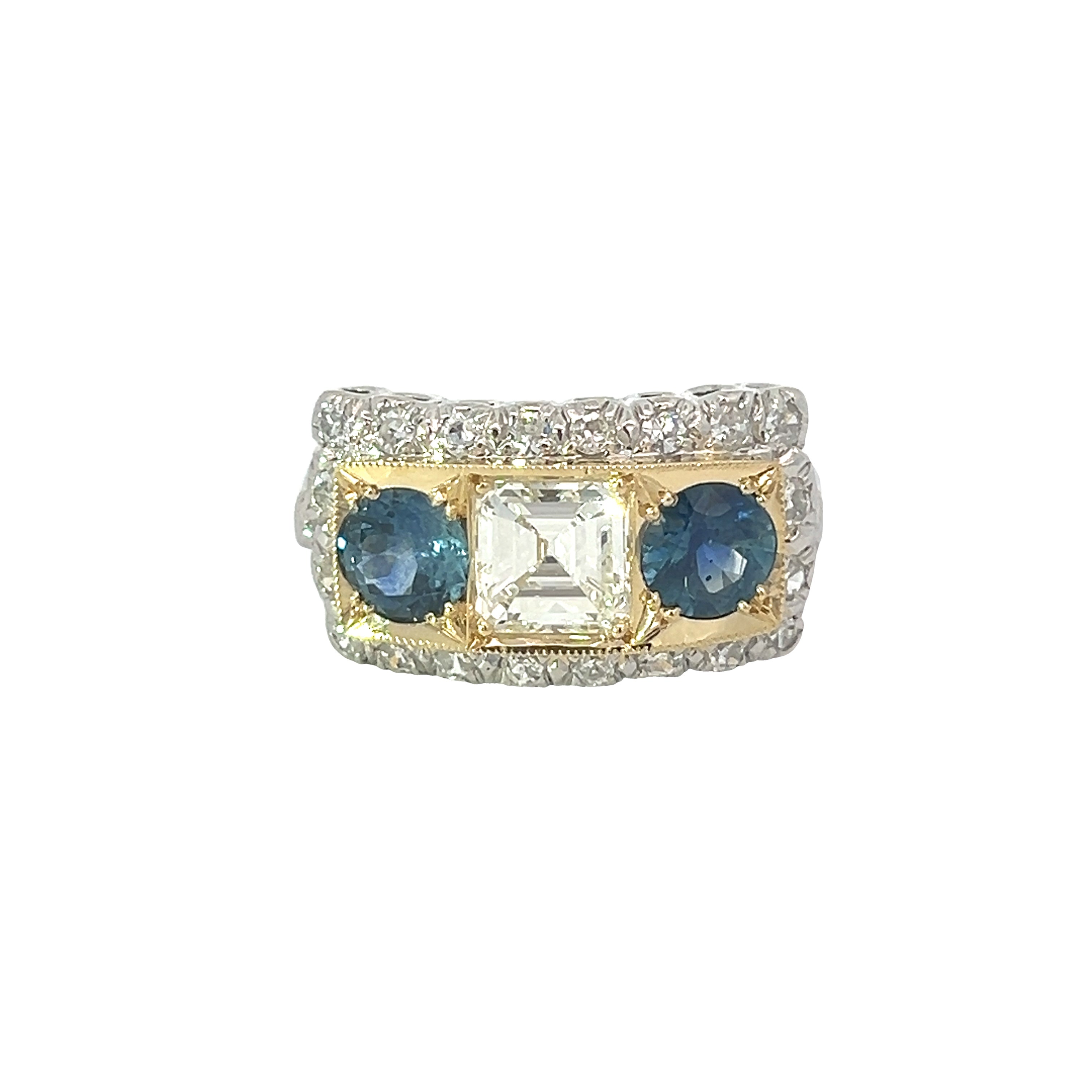 The "Late Century Platinum/18kt Yellow Gold Ring" showcases a stunning 1.11-carat Asscher cut diamond of VS clarity and H color at its center, flanked by two round Montana sapphires totaling 1.83 carats. The band is encrusted with an additional .75 carats of small diamonds, creating a sparkling design with vintage charm.
