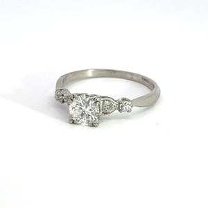 The Art Deco Platinum ring boasts a .50-carat Old European Cut diamond at its center, flanked by two smaller Old Mine Cut diamonds totaling .28 carats. This vintage-inspired engagement ring is set on a slender band and displayed against a white background.