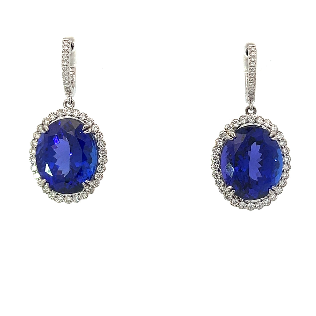 The Modern 18kt White Gold 22.25ct Tanzanite + .87cttw Diamond Earrings showcase large, oval-shaped deep blue tanzanites surrounded by intricate settings of small diamonds. The gemstones are elegantly suspended from diamond-studded hooks crafted in modern 18kt white gold, giving the earrings a timeless and luxurious appearance.