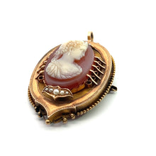 Load image into Gallery viewer, The Victorian 14ktyg Carved Agate Portrait of a Lady Cameo is an antique gold pendant showcasing a classical woman&#39;s profile carved in white relief against a reddish-brown background. This oval-shaped Victorian jewelry piece is framed with ornate 14kt yellow gold, adorned with small pearls and featuring intricate detailing.