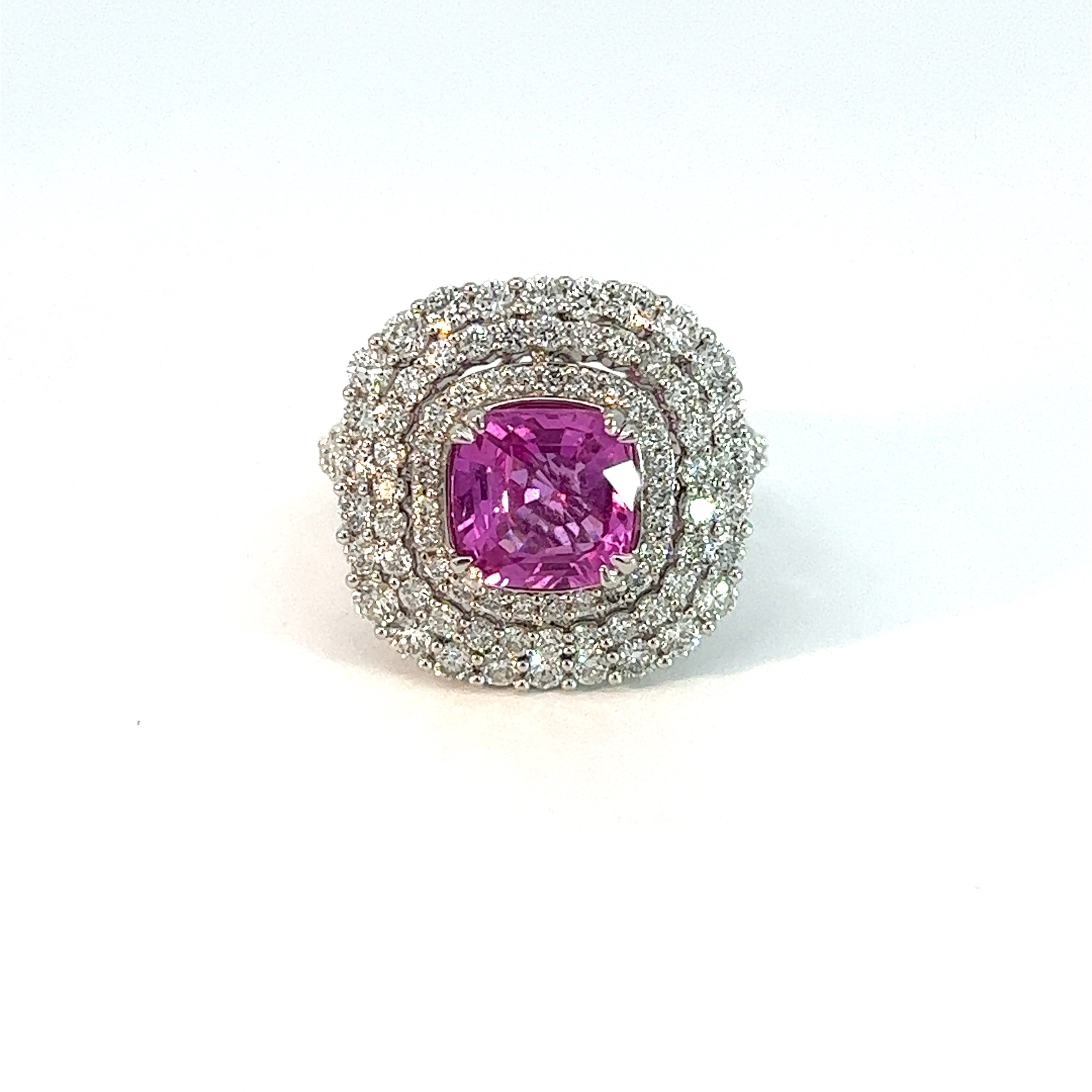 The Modern 14kt white gold ring boasts a stunning 2.28ct no-heat pink sapphire at its center, encircled by 1.25cttw diamonds in elegant concentric patterns, all set in a sleek, silver band.