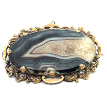 Load image into Gallery viewer, An elegant Victorian 10kt yellow gold pendant/pin featuring a large banded agate stone with intricate shades of gray, white, and beige. The stone is set in an ornate gold-toned metal frame adorned with detailed floral and scrollwork designs.