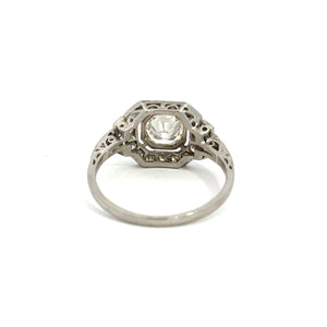 The Late Art Deco Platinum .91ct Round Brilliant Cut Diamond + 1.16cttw Diamond Ring, featuring a large central gemstone and intricate filigree design, is displayed on a plain white background. This ring showcases vintage sophistication and detailed craftsmanship with its delicate patterns and Art Deco elegance.