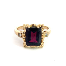 Load image into Gallery viewer, A Mid Century 14kt Yellow Gold Ring featuring a large, rectangular, 4.80ct dark red garnet gemstone at its center. The garnet is surrounded by intricate gold detailing and accented with small, sparkling diamonds totaling .06cttw on either side, set on a plain gold band. This exquisite ring is displayed on a plain white background.