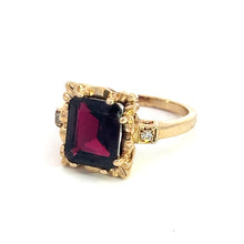 Load image into Gallery viewer, Introducing the Mid Century 14ktyg 4.80ct Garnet + .06cttw Diamond Ring: a stunning gold ring featuring a 4.80-carat garnet set in an ornate bezel with delicate details. The 14kt yellow gold band, inspired by mid-century design, is embellished with small round diamonds totaling .06 carats on either side of the dark red central gemstone. The overall design exudes elegance and intricacy.