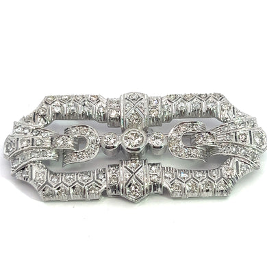 An intricately designed Art Deco Platinum Brooch featuring 3.65cttw of Old Euro, Old Mine, and Antique Cut Diamonds. The brooch showcases geometric patterns and a symmetrical, ornate structure with a central clasp, exuding vintage elegance through its detailed craftsmanship.