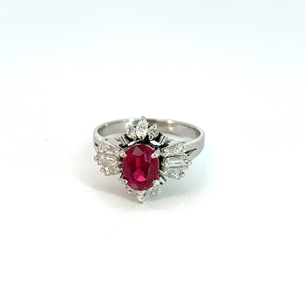 Introducing the Mid Century Platinum 1.34ct Ruby and .57cttw Diamond Ring—an exquisite handcrafted luxury piece. This stunning ring features a prominent oval vivid red ruby at its center, encircled by small, sparkling diamond accents that form an elegant floral pattern around it. Photographed against a plain white background, this ring showcases timeless beauty and sophistication.