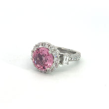 Load image into Gallery viewer, The Modern Platinum 3.30 No Heat Padparadscha Sapphire Ring features an exquisite, rare gemstone as its centerpiece: a large, round pink no-heat Padparadscha sapphire surrounded by smaller clear diamonds in a halo setting. The band is adorned with additional clear diamonds and rectangular side stones.