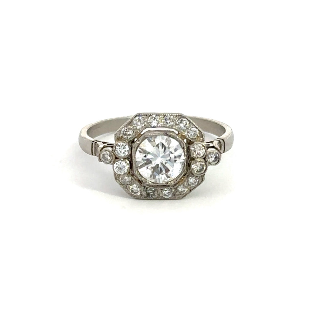 The Art Deco Platinum .80ct Round Brilliant Cut + 1.08cttw Diamond Ring showcases a dazzling round brilliant cut diamond at its center, encircled by a halo of smaller diamonds arranged in an intricate geometric pattern on the band.