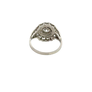 A late Art Deco silver ring, named the Late Art Deco .90ct Round Brilliant Cut Diamond + 1.96cttw Diamonds Black Enamel Ring, displays an ornate design with a central circular round brilliant cut diamond setting, viewed from the side. The thin band supports an intricate setting that elevates the gemstone, highlighted by detailed metalwork and black enamel reminiscent of vintage luxury. The background is plain white.