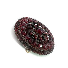 Load image into Gallery viewer, The Victorian Vermeil Oval Garnet Brooch features a dense cluster of deep red gemstones arranged in a layered, intricate design. The gold-tone clasp and backing add vintage charm, while the deep color of the gems creates a striking and elegant appearance. The brooch is set against a plain white background.