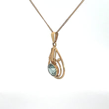 Load image into Gallery viewer, The Art Nouveau 14kt Yellow Gold 2ct Blue Zircon Necklace showcases a delicate pendant with an elegant open swirl design, encasing a light blue zircon gemstone. This stunning pendant is suspended from a fine gold chain against a plain white background.