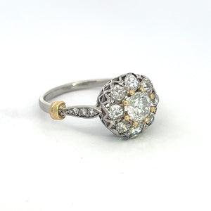 Introducing the exquisite Edwardian Platinum & 18kt Yellow Gold 1.30cttw Old Mine Cut Diamond Ring: This stunning piece features a large, round central old mine cut diamond, elegantly surrounded by a halo of smaller diamonds. The intricately detailed band is crafted from platinum and 18kt yellow gold, showcasing delicate workmanship and a subtle gold accent near the setting. Displayed against a plain white background, this ring exudes timeless elegance and sophistication.