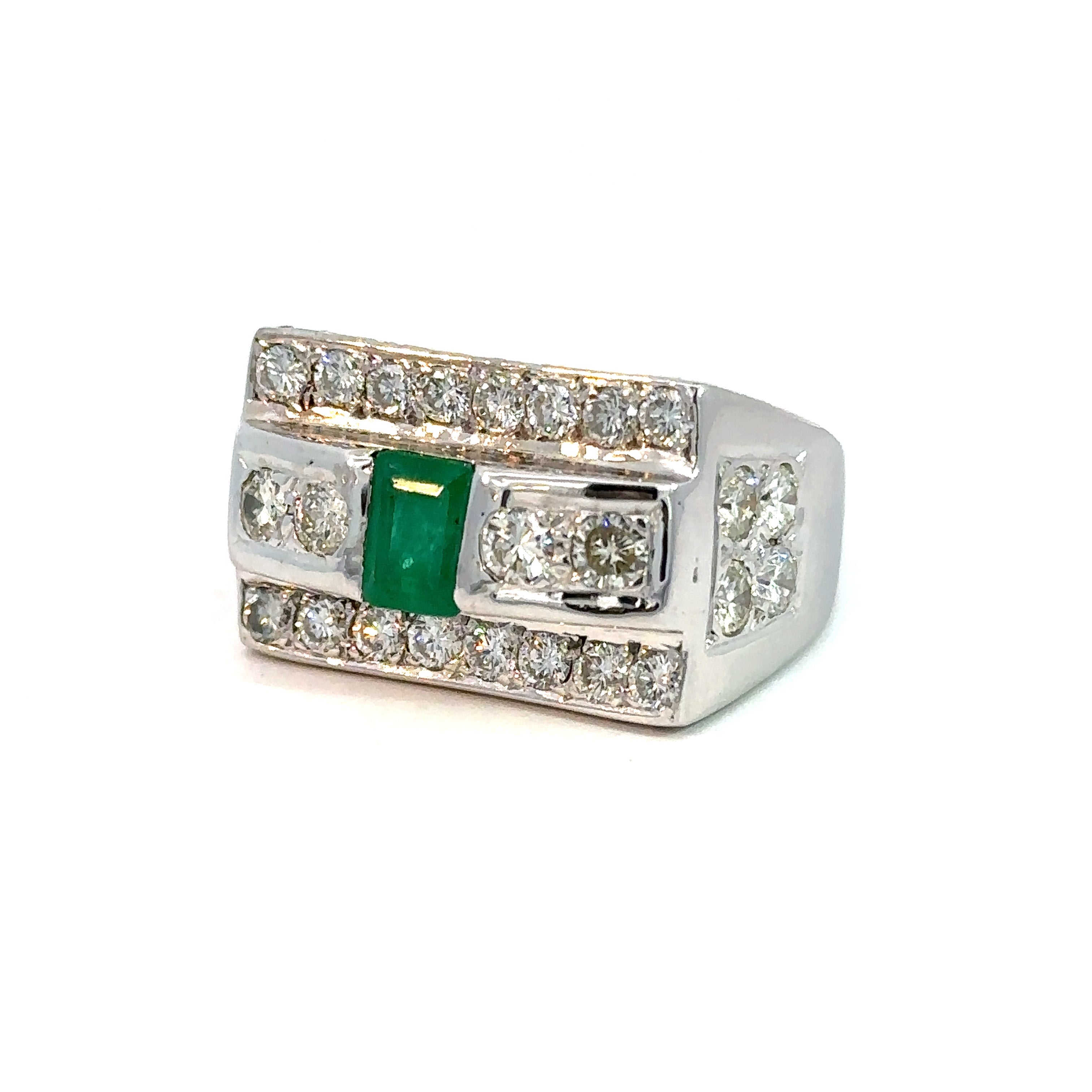 A striking Late Century 14kt white gold ring featuring a central 1ct emerald-cut emerald, flanked by two smaller diamonds. The broad band is adorned with rows of small diamonds on the top and bottom edges, contributing to its ornate design. This Emerald and Diamond Ring, set against a plain white background, showcases a total diamond weight of 5.70 carats in round brilliant cuts.
