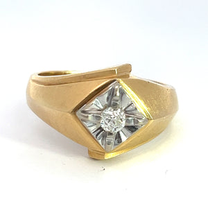 The "Late Century 14kt Two Tone Gold .25ct Old Mine Cut Diamond Ring" showcases a distinctive asymmetrical design. Its centerpiece, a small round old mine cut diamond, is set in a recessed geometric pattern adorned with silver-toned accents. The broad, smooth band features gentle curves that enhance its vintage appeal.