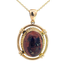 Load image into Gallery viewer, This Late Century 14kt Yellow Gold 5ct Boulder Opal Fancy Frame Pendant is a gold necklace with a vintage charm pendant, featuring an oval-shaped, polished boulder opal gemstone showcasing a marbled pattern of dark blue and reddish hues. The intricately designed frame holds the gemstone securely in place with four clasps.