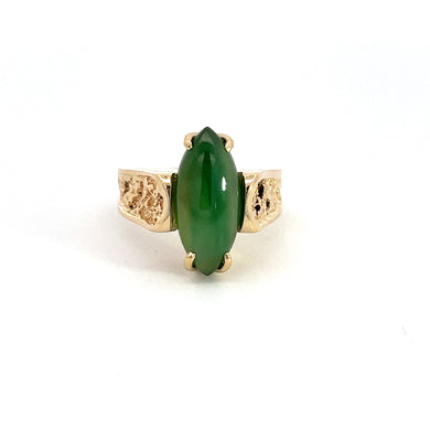 The Late Century 18kt Yellow Gold Nugget Style Jadeite Jade Ring features an elongated, oval-shaped green Jadeite Jade gemstone set at its center. The 18kt yellow gold nugget band boasts intricate, textured floral designs on both sides of the gemstone, creating an elegant and ornate appearance against a plain white background.