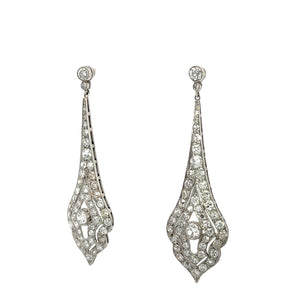 The Art Deco Platinum 8cttw Old Mine Cut & Antique Cut Diamond Drop Earrings feature an elegant, vintage style with intricate teardrop designs adorned with numerous small, sparkling diamonds. Their delicate, lacy appearance is completed with a round stone at the top connecting to the teardrop shapes below.