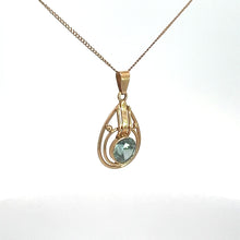 Load image into Gallery viewer, The Art Nouveau 14kt Yellow Gold 2ct Blue Zircon Necklace features a delicate and fine yellow gold chain, elegantly contrasting with an ornate teardrop-shaped pendant. The intricate design of the pendant beautifully cradles a stunning light blue zircon gemstone at its center, set against a plain white background to highlight its elegance.