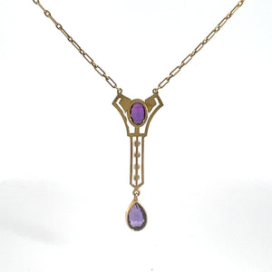 This Victorian 14kt Yellow Gold 3.50cttw Amethyst Pearl Lavalier Necklace features an ornate pendant adorned with an oval-shaped amethyst at the center and a teardrop-shaped purple gemstone elegantly dangling below. The chain is composed of small interlocking links.