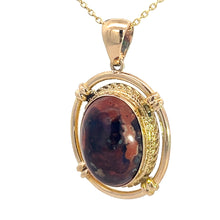 Load image into Gallery viewer, Introducing the Late Century 14kt Yellow Gold 5ct Boulder Opal Fancy Frame Pendant, featuring an oval-shaped, polished boulder opal with a marbled appearance in dark red, brown, and black hues. The stone is set in a gold-colored mount with a decorative frame and chain, exuding vintage charm.