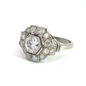 The Art Deco Platinum .91ct Old European Cut Diamond + 1.60cttw Diamond Ring boasts an elegant central old European cut diamond, surrounded by a sophisticated octagonal arrangement of smaller diamonds. Its intricate geometric design gives it a vintage, Art Deco jewelry charm against a white background.