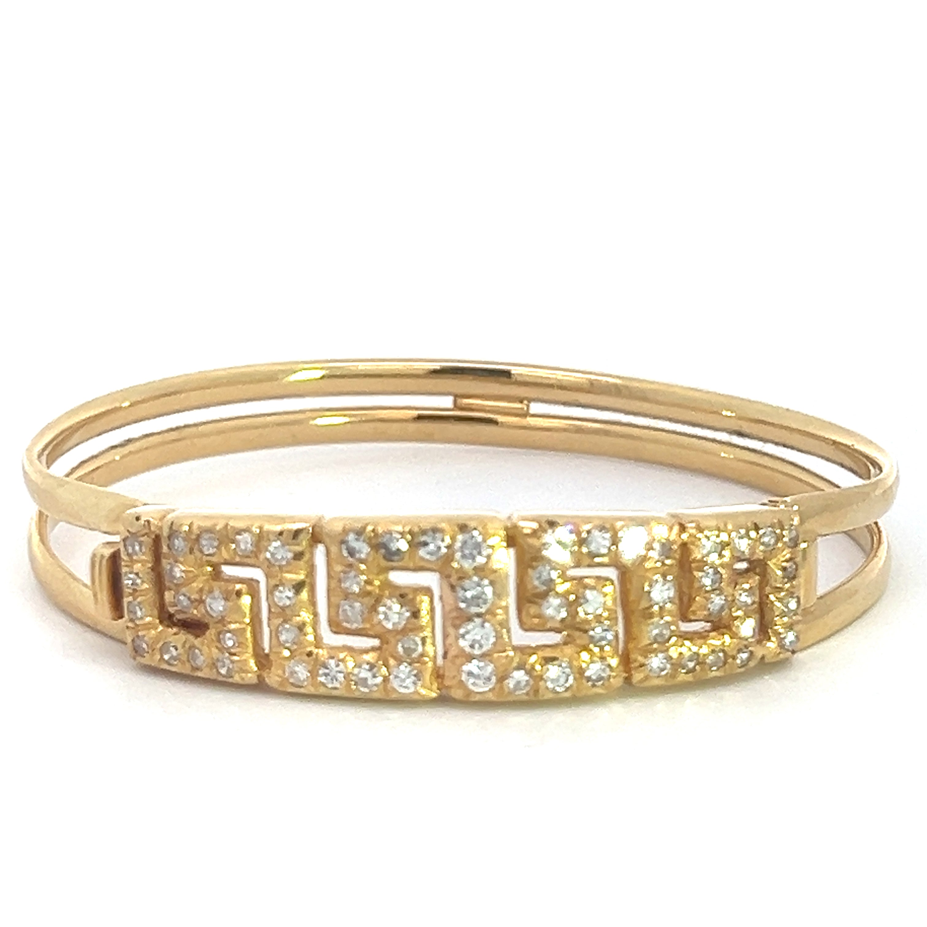 The Late Century 18ktyg 1.80cttw Greek Key Diamond Bangle Bracelet is showcased against a white background, highlighting its geometric design and shimmering small diamonds. This exquisite 18k yellow gold bracelet features two slender, smooth gold bands that converge at a central section intricately detailed in the Greek Key pattern and adorned with sparkling gemstones, evoking the elegance of a Late Century diamond bangle.