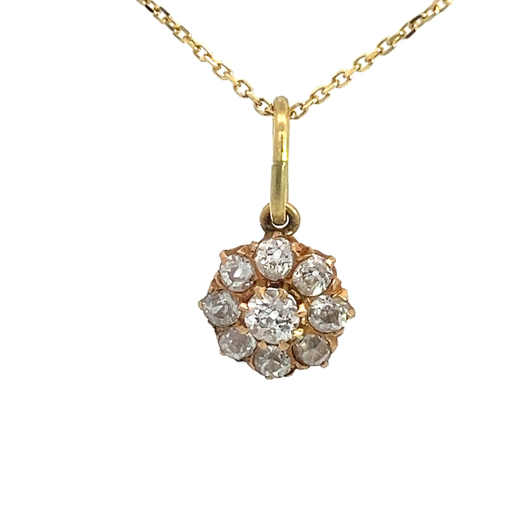 A Victorian 14kt yellow gold necklace showcasing a pendant adorned with a cluster of nine small, round old mine cut diamonds totaling 1.16 carats and arranged in a charming flower-like design. The timeless pendant is suspended elegantly from a delicate gold chain, all set against a white background.

