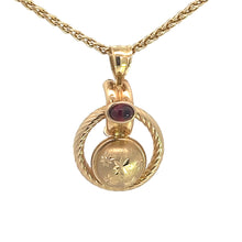 Load image into Gallery viewer, The Victorian 14kt yellow gold pendant necklace features a circular locket adorned with exquisite floral engravings and a small oval cabochon garnet at the top. This elegant design is complemented by a diamond-cut finish and hangs from an 18-inch twisted gold chain.