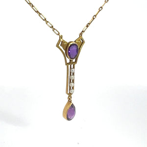 This 14kt yellow gold necklace is a Victorian jewelry masterpiece, showcasing an ornate pendant adorned with a striking purple oval gemstone. Dangling below are three delicate pearls that lead to a teardrop-shaped amethyst at the bottom. The entire piece is suspended from a gold chain with elegant rectangular links, making it an exquisite Amethyst and Pearl Lavalier Necklace.