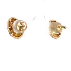 Close-up image of a pair of Art Deco 14kt yellow gold .50cttw Old European Cut diamond stud earrings with butterfly backs. The earrings are attached to a transparent display holder, with their front sides facing towards the background and the backs clearly visible. The background is plain white.