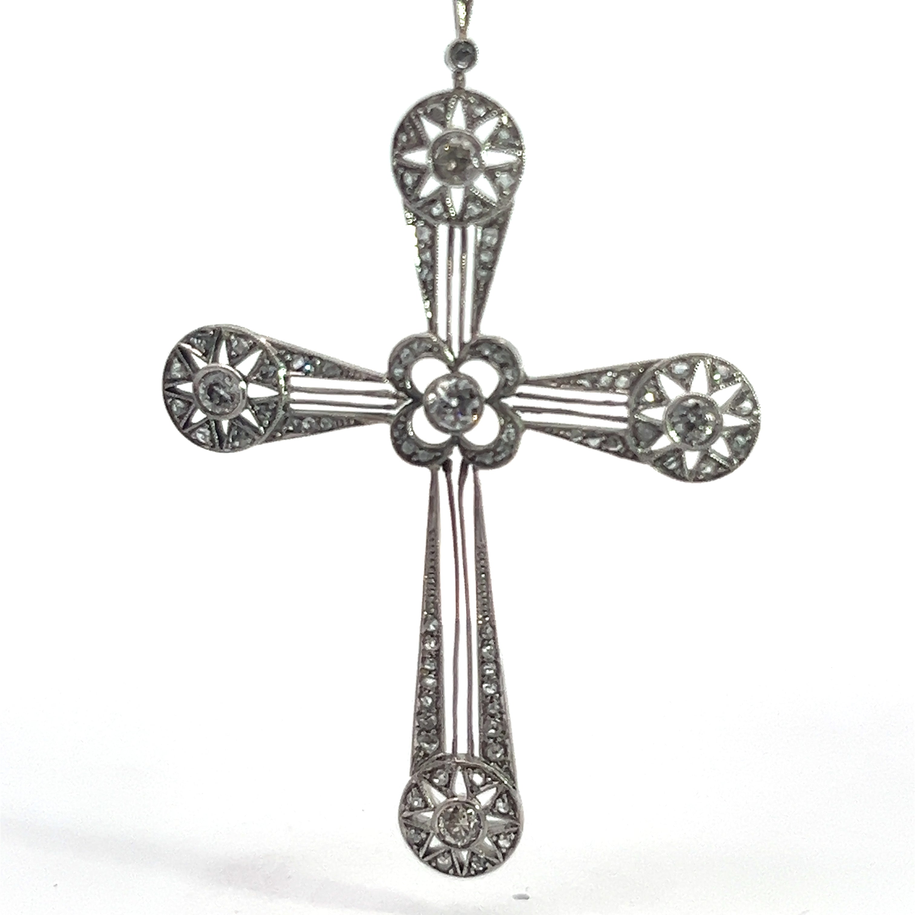 An exquisite Art Deco Platinum cross pendant adorned with intricate designs and set with 3.35ct Old European Cut and Rose Cut diamonds. The cross features circular floral patterns at the ends of each arm and in the center, interconnected by narrow, straight lines.