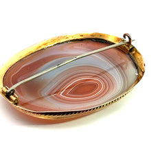 Load image into Gallery viewer, The Victorian 14ktyg Large Banded Agate Pin is an oval brooch with a polished banded agate stone, set in a 14kt yellow gold-colored border. The agate showcases concentric natural patterns in shades of brown and white, reminiscent of Victorian-era jewelry. The brooch pin is visible on the back.